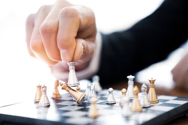 Hombre de negocios sujeta piezas de ajedrez. Analiza la jugada.
