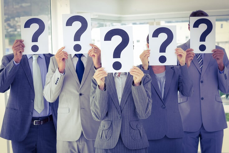 Compañeros de trabajo sosteniendo carteles con signos de interrogación en la oficina 